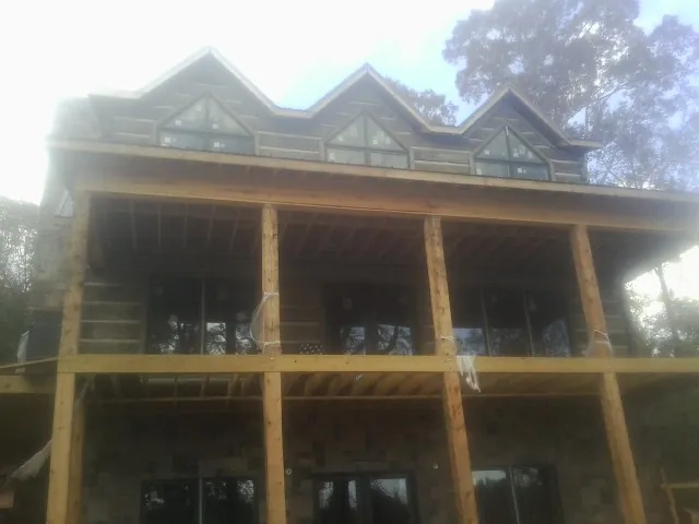 Dormers and porch framing on a large log home under construction — Roof Coating work by our crew in Dougherty