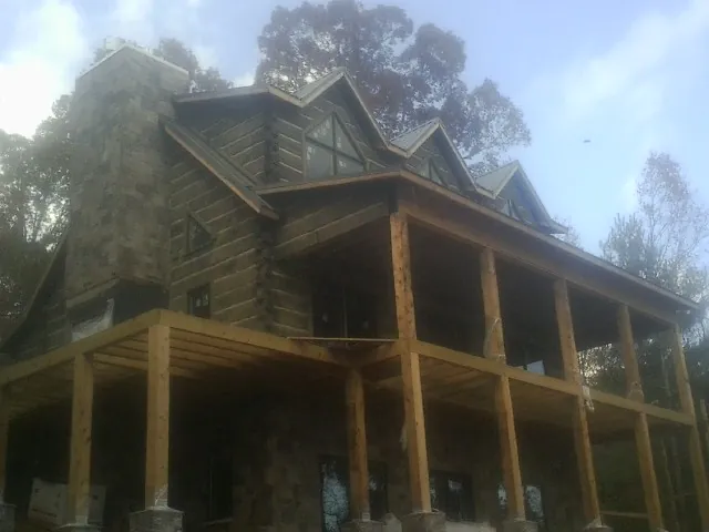 Stone chimney and dormers on a large log home with a timber porch in Dougherty