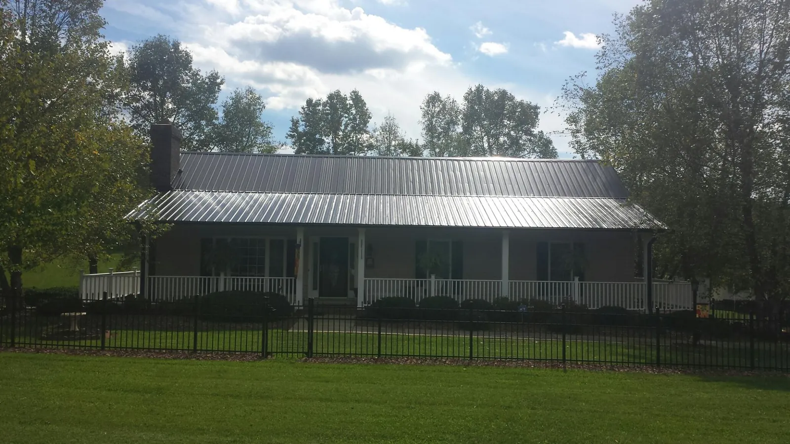 Gray metal roof on a brick ranch with a full width front porch — Gutter Guard Installation work by our crew in Dougherty