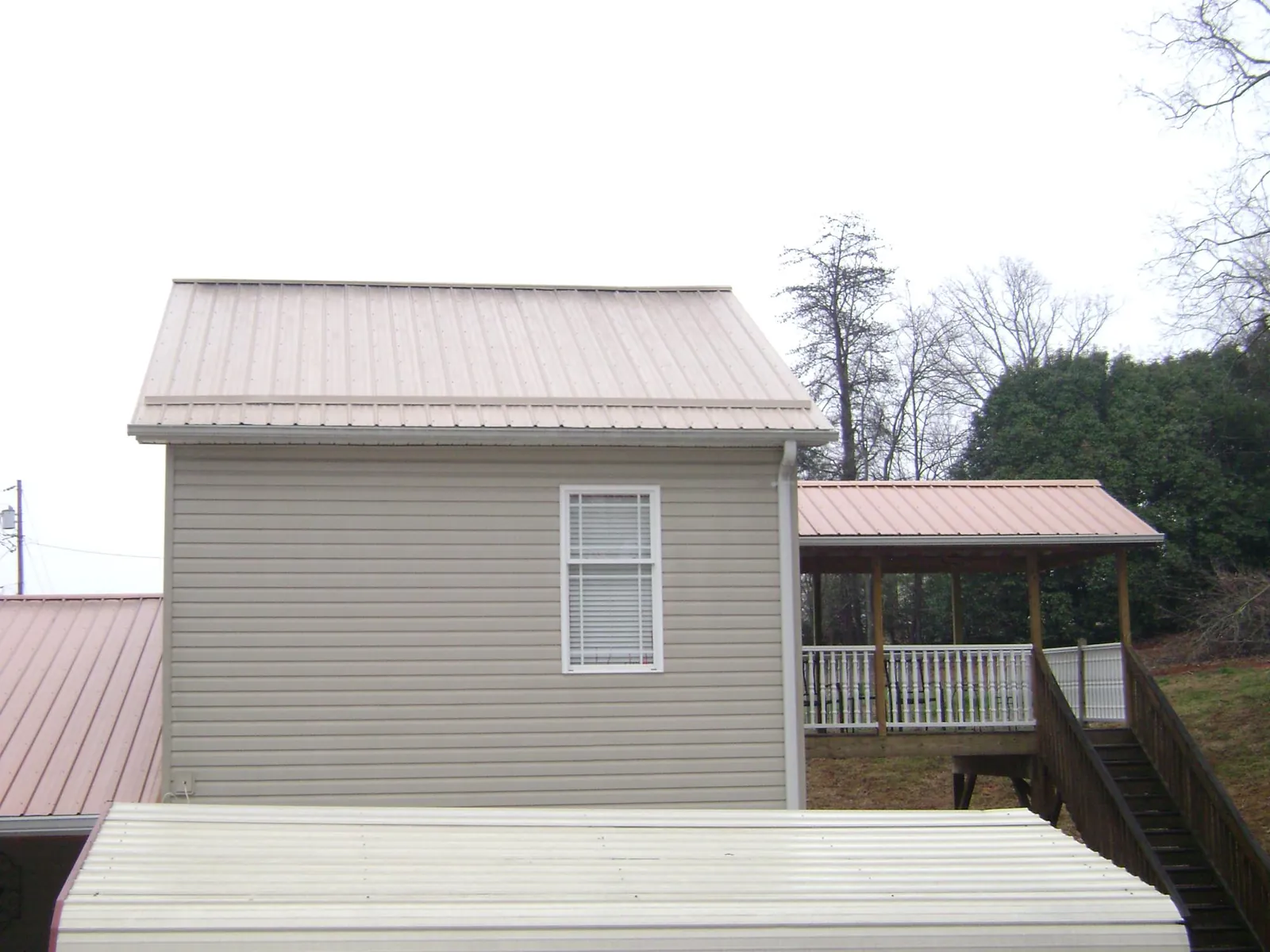 Tan metal roofs on a two story addition and attached porch, from a Roof Replacement job in Dougherty